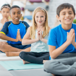 3 Kinder sitzen im Schneidersitz und meditieren