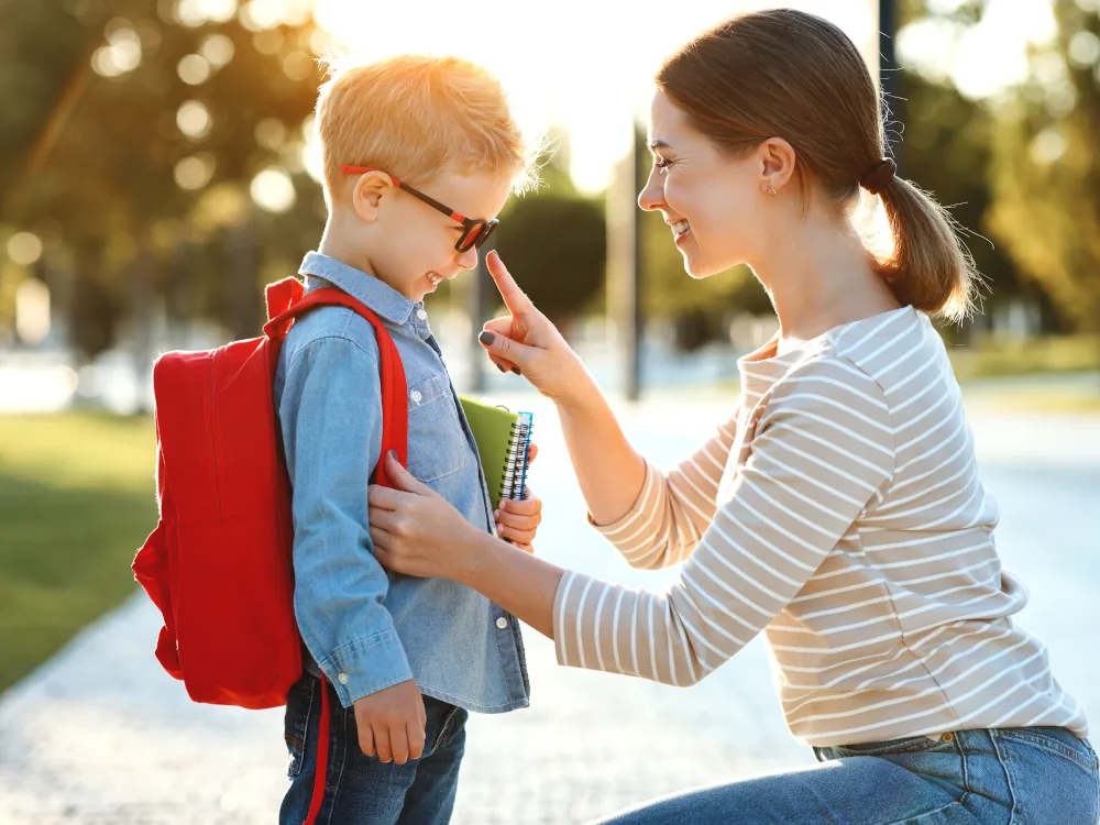 Kind wird vor Schule von seiner Mama verabschiedet